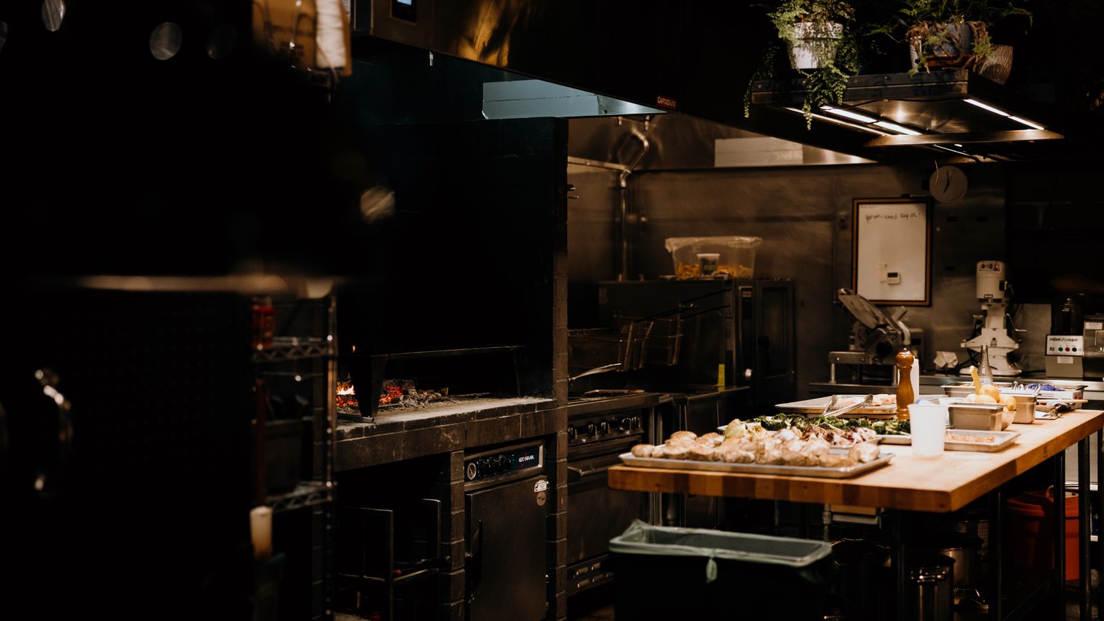 A quiet restaurant kitchen with prep laid out and nobody working, the dead hours between services where labor hours go unnoticed